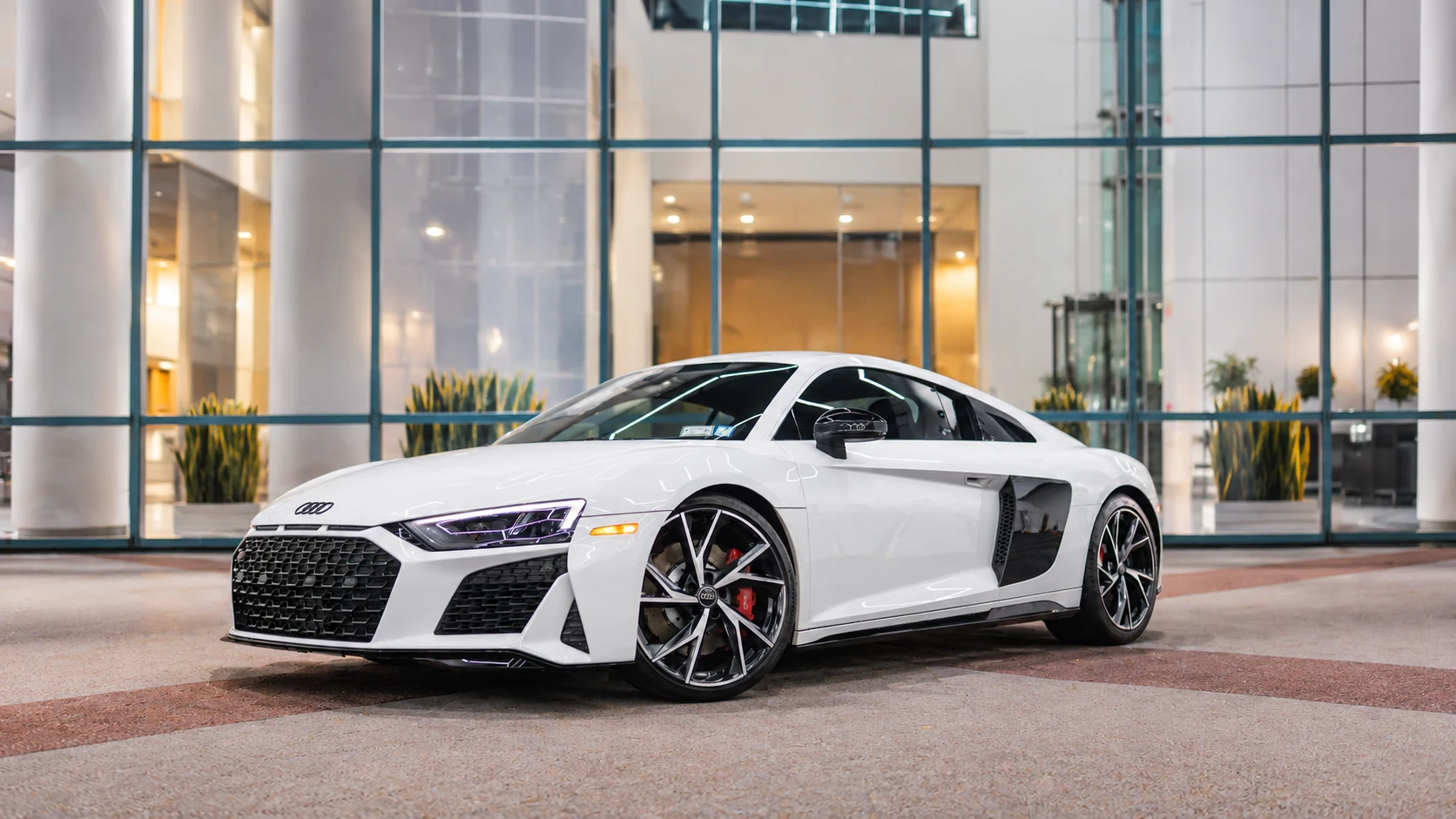 White Audi R8 V10 in an edited glass-front showroom setting